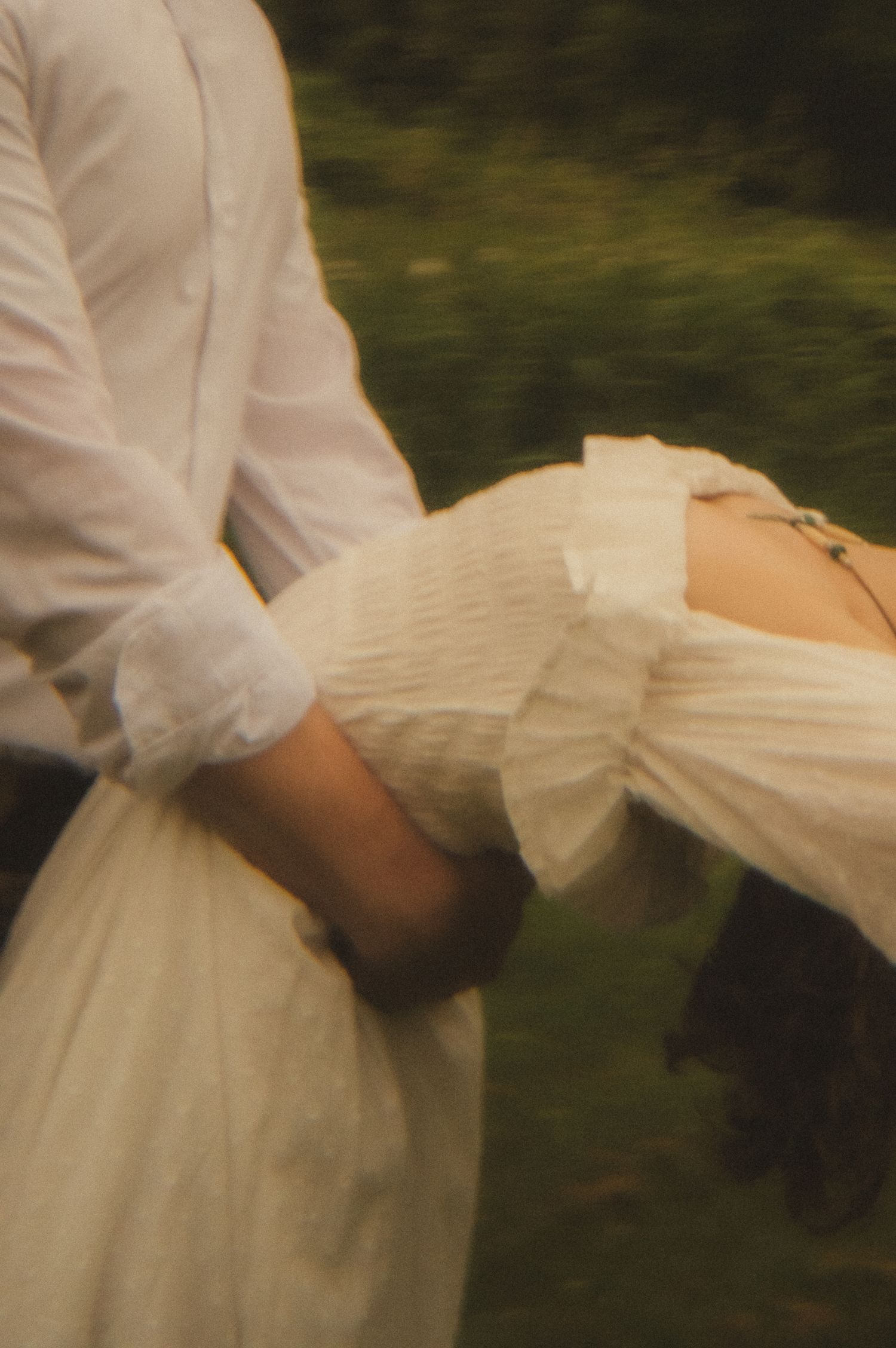 A series of blurred images showing the flowing movement of a white dress and fabric in an outdoor setting.