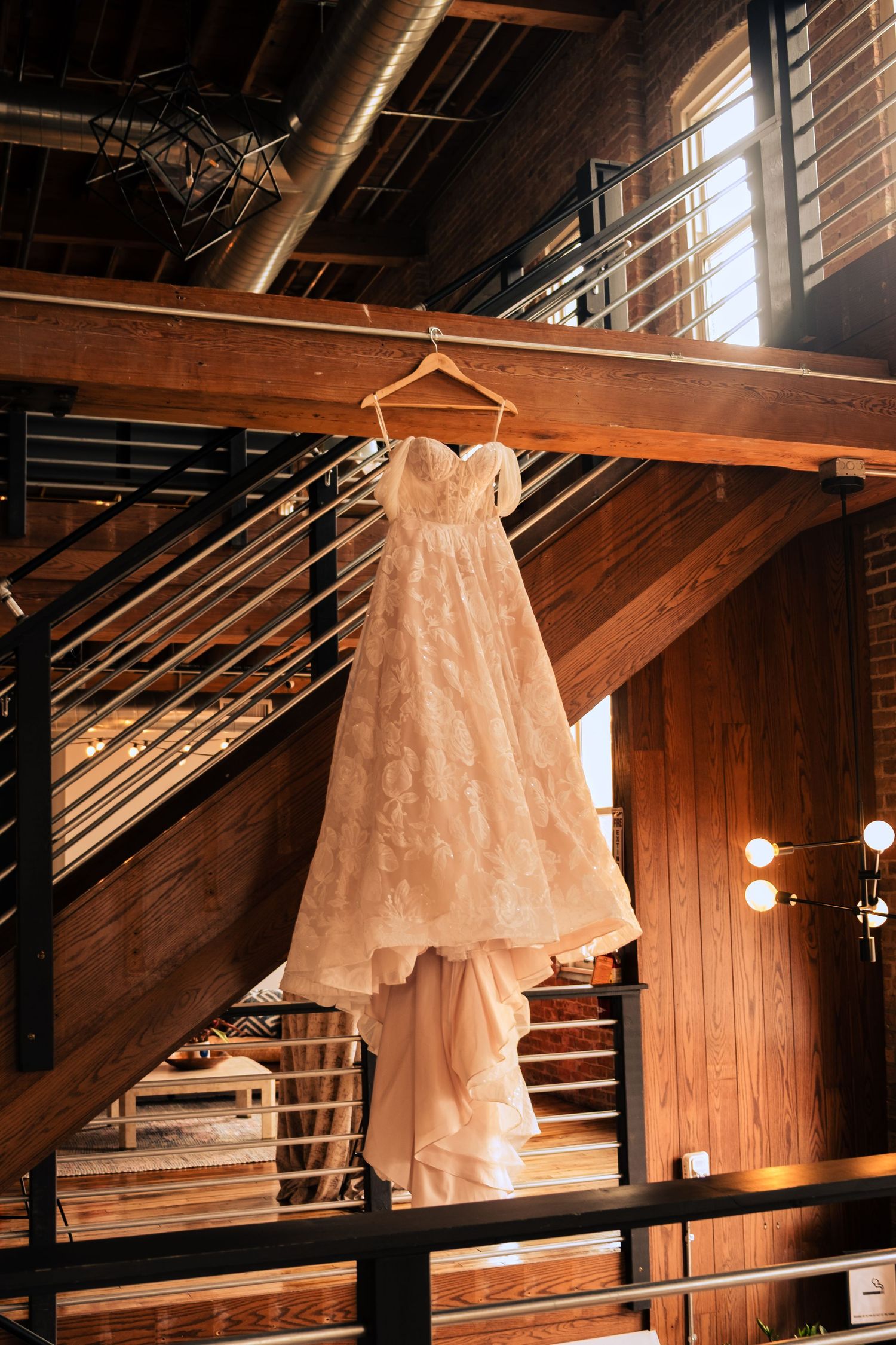 Three vintage white wedding dresses displayed on hangers in a rustic wooden attic or barn setting.