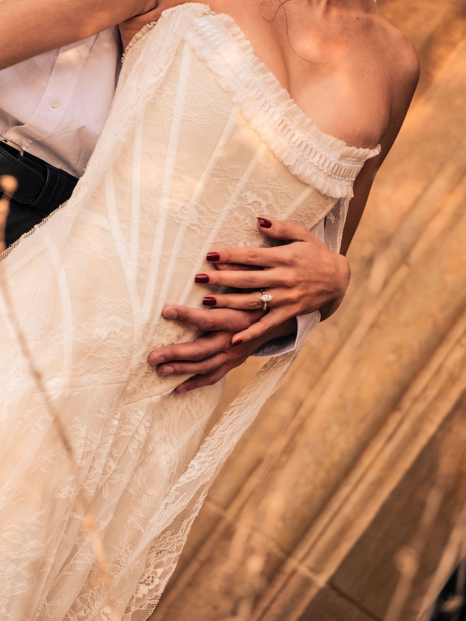 Close-up details of a white lace wedding dress being held delicately to show intricate patterns and textures.