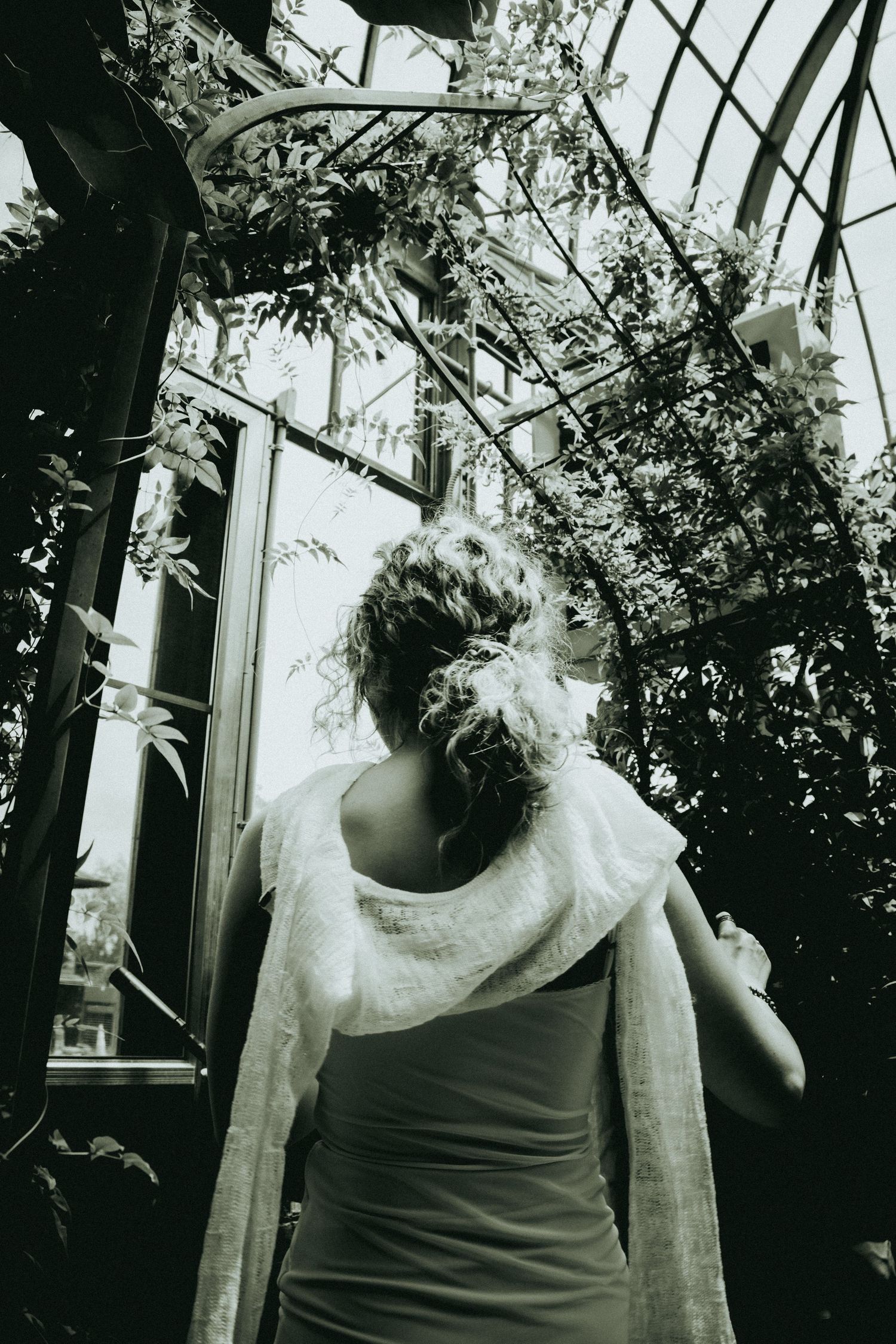 A black and white photo series showing a person in a tank top with plants and shadows creating a moody atmosphere.