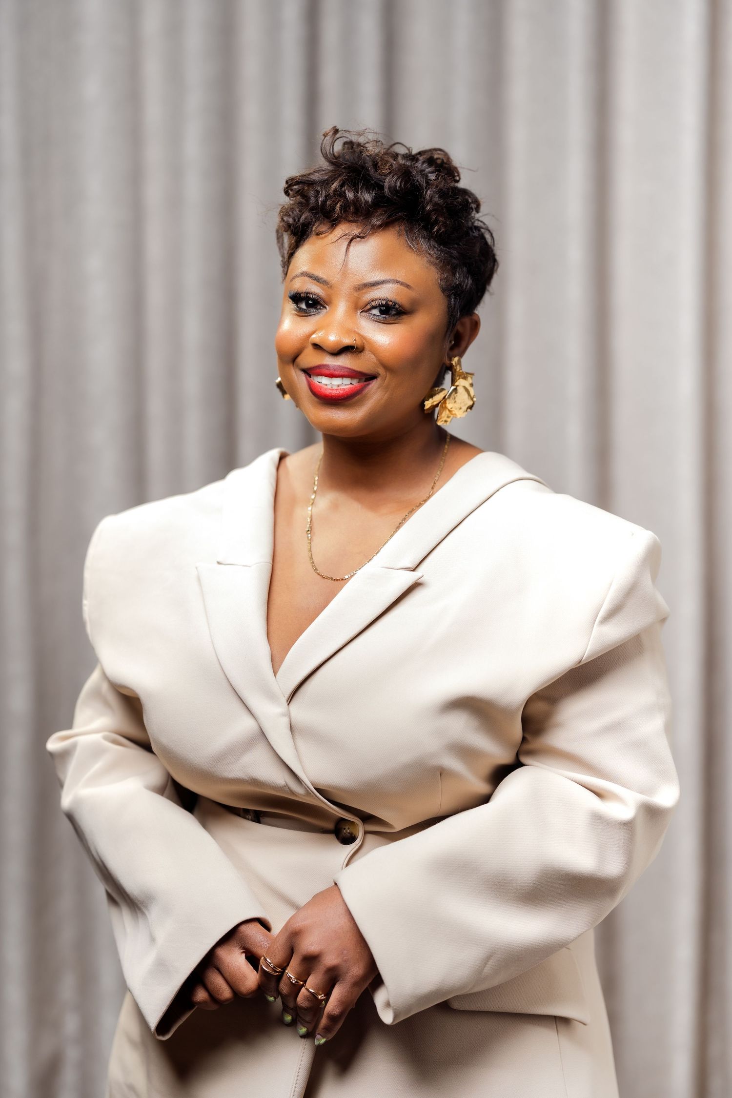 A portrait of a black woman in a cream blazer