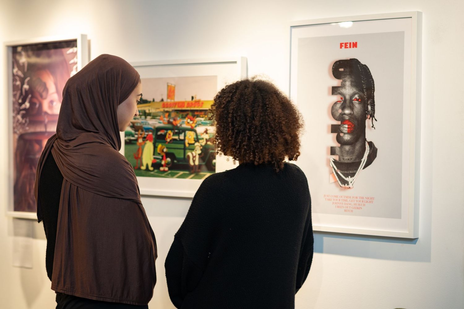 Two women are looking at art on a wall