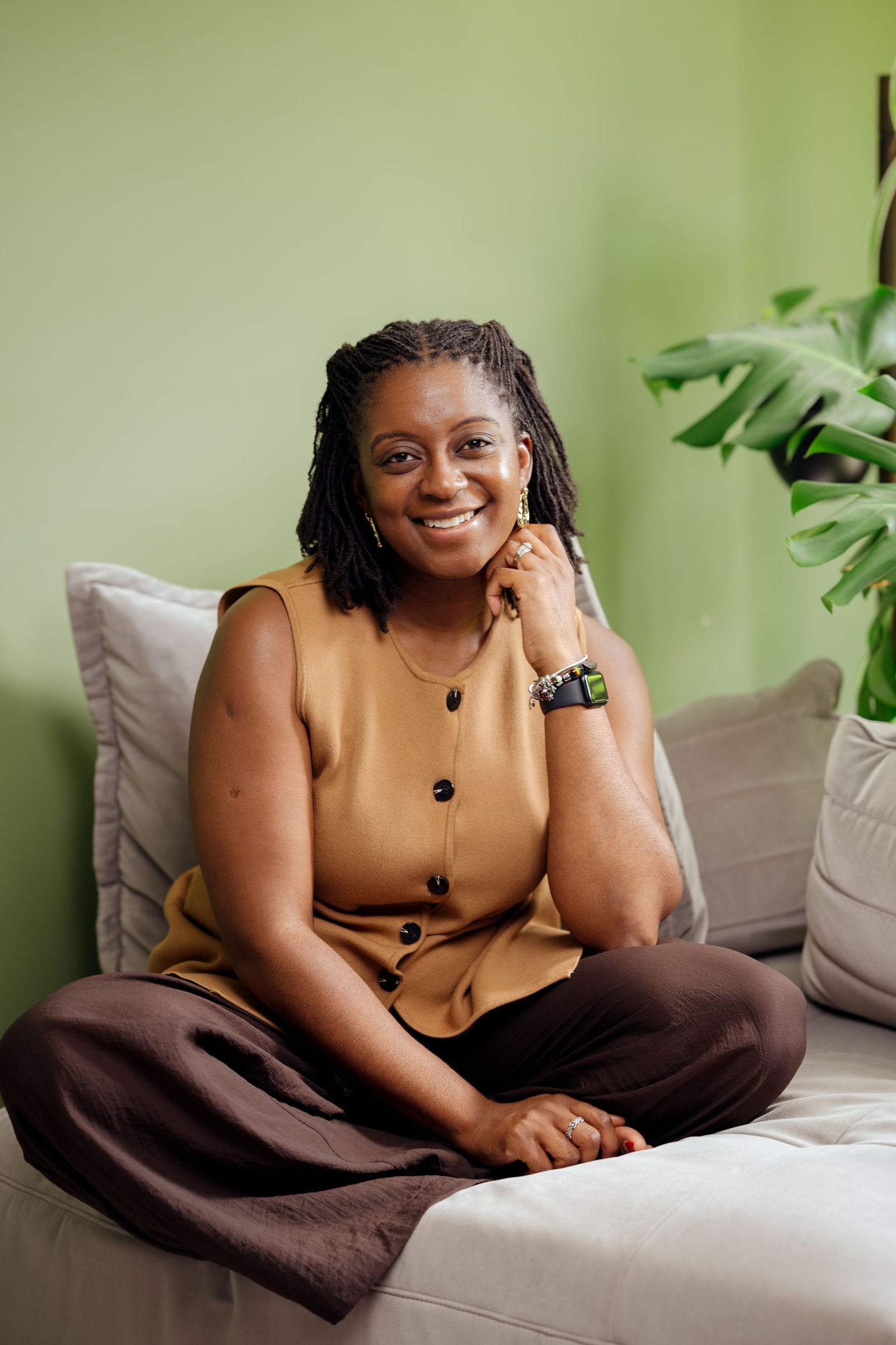Portrait of a black woman sitting cross-legged on a sofa