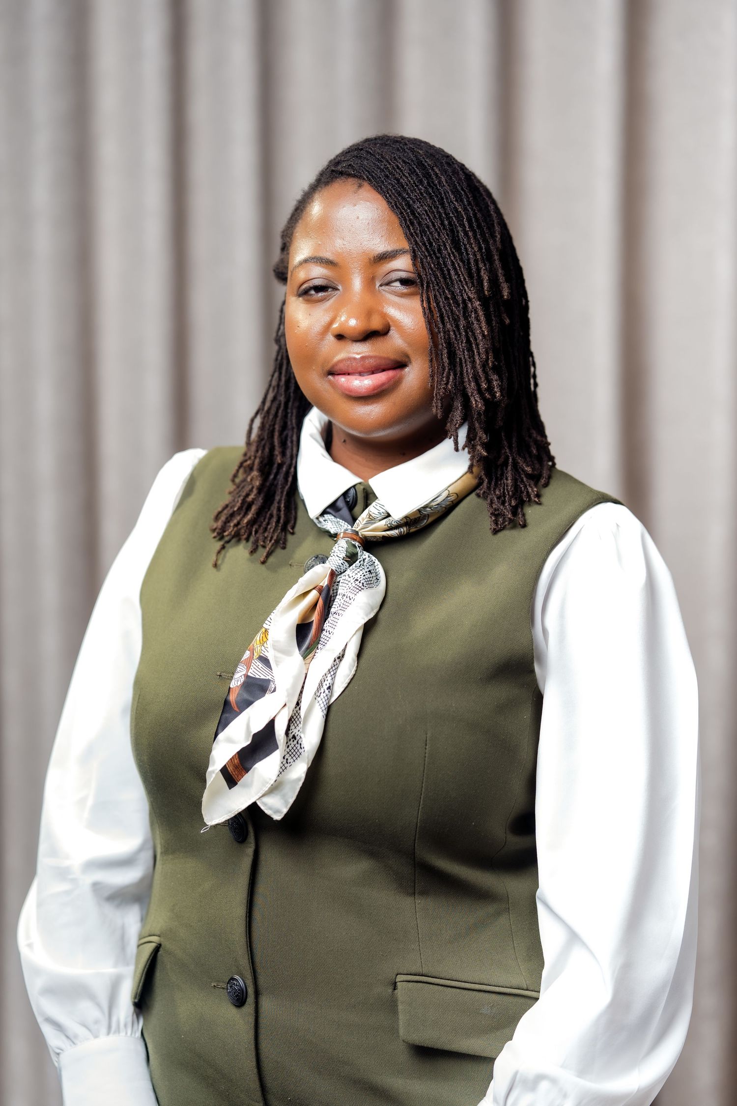 A portrait of a black woman in a green waistcoat and a white shirt