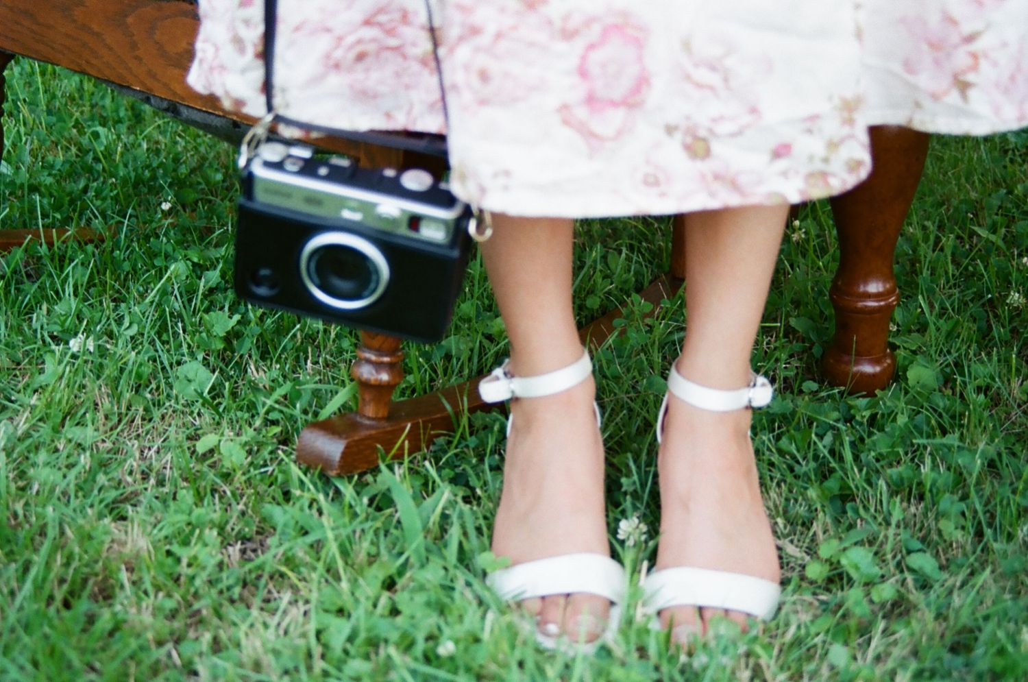 Close-up detail of children's white socks and shiny black mary jane shoes worn on grass.