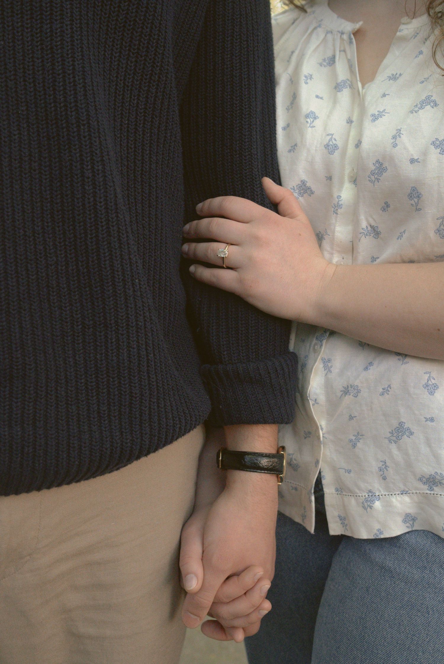 Close-up sequence of hands holding each other tenderly while wearing contrasting light and dark sleeve garments.