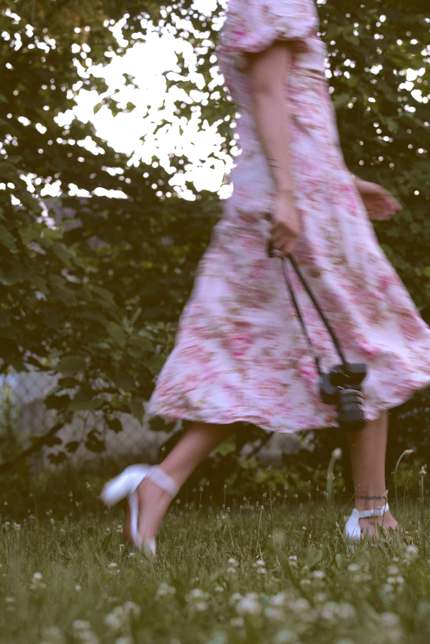 A whimsical sequence of a flowing dress twirling in motion across green grass, captured in a dreamy vintage style.