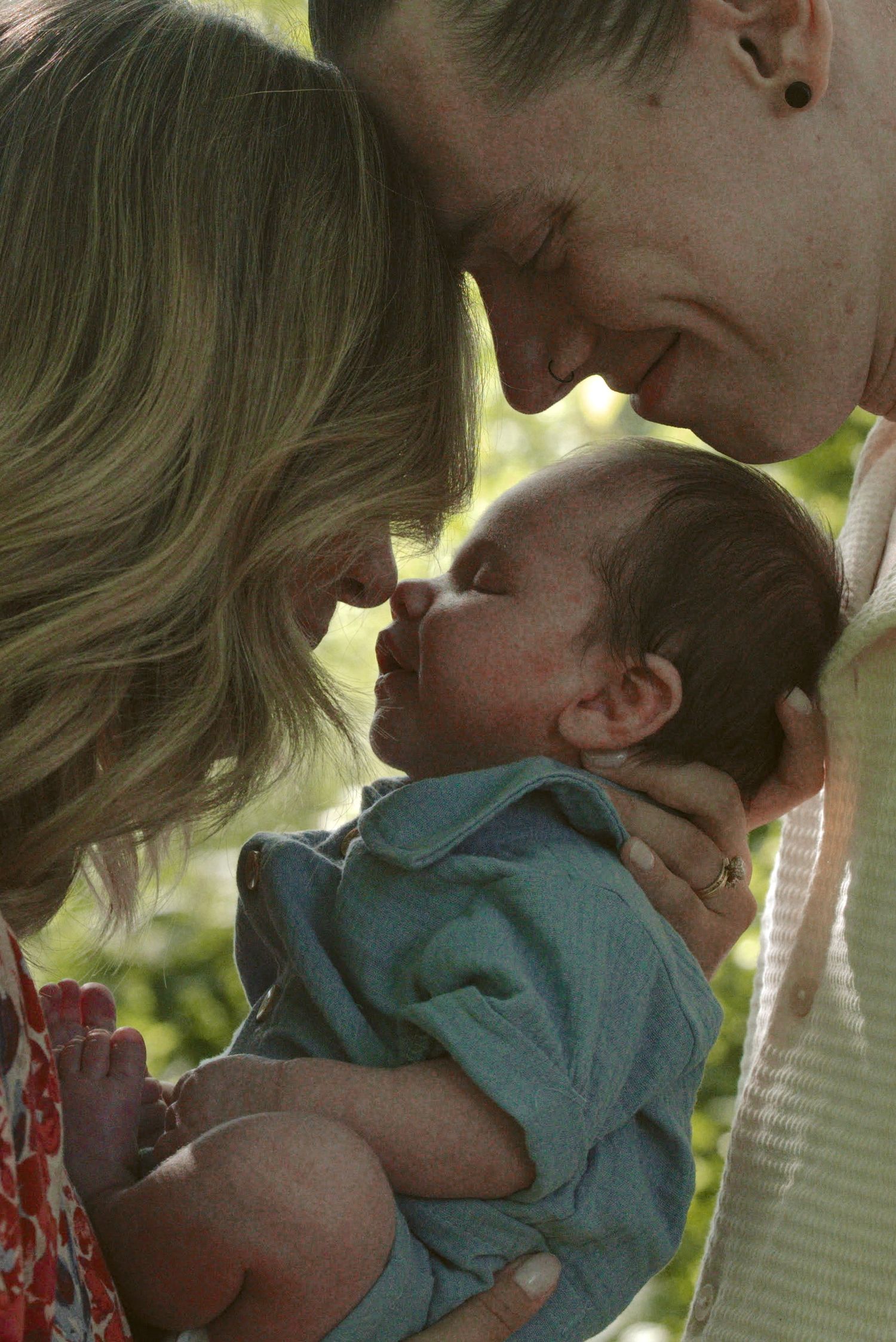 Tender family moment showing parent kissing small child outdoors in natural lighting.