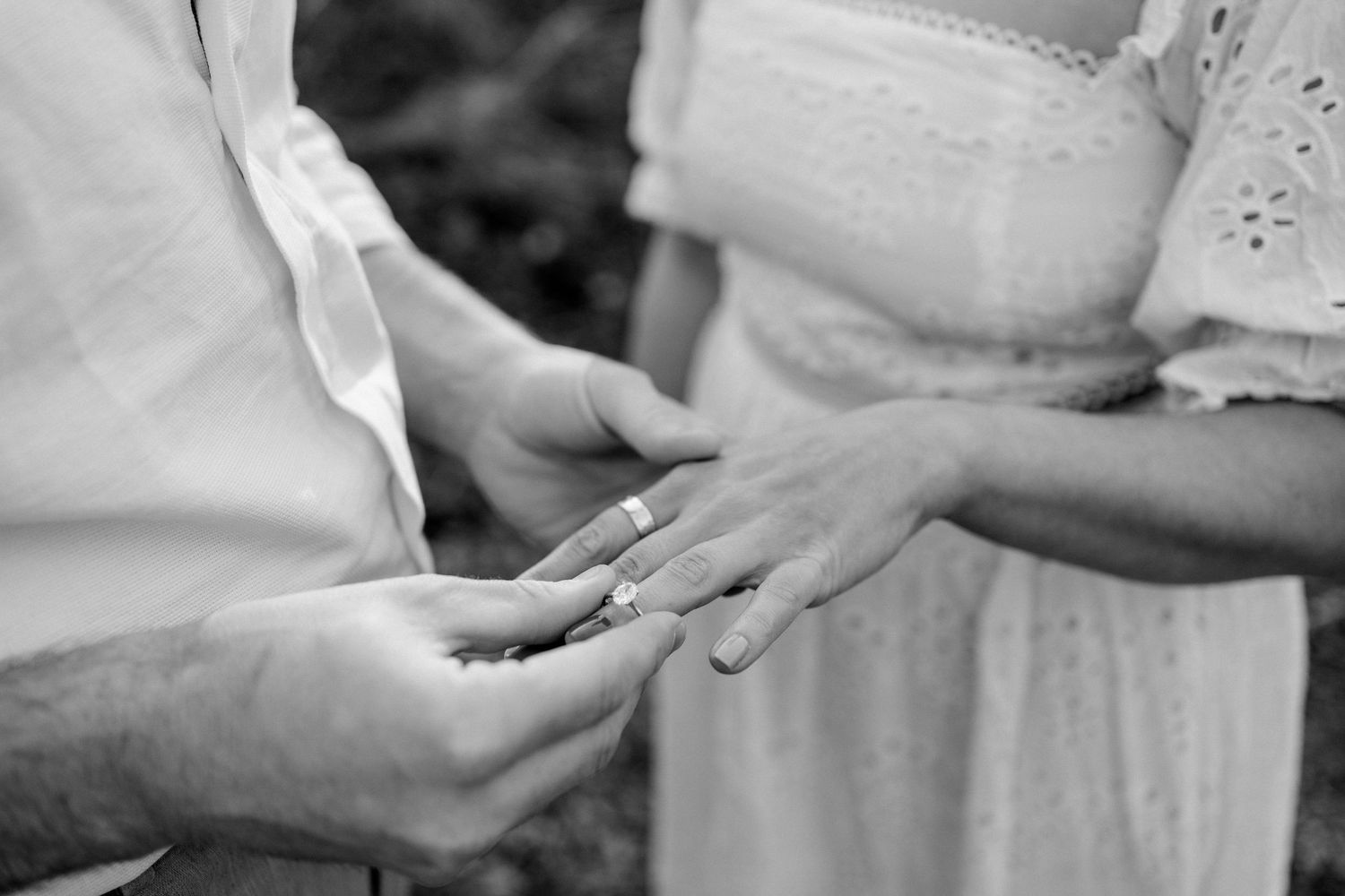 Male putting an engagement ring on a female hand during their engagement photoshoot in Bourne Woods, Surrey
