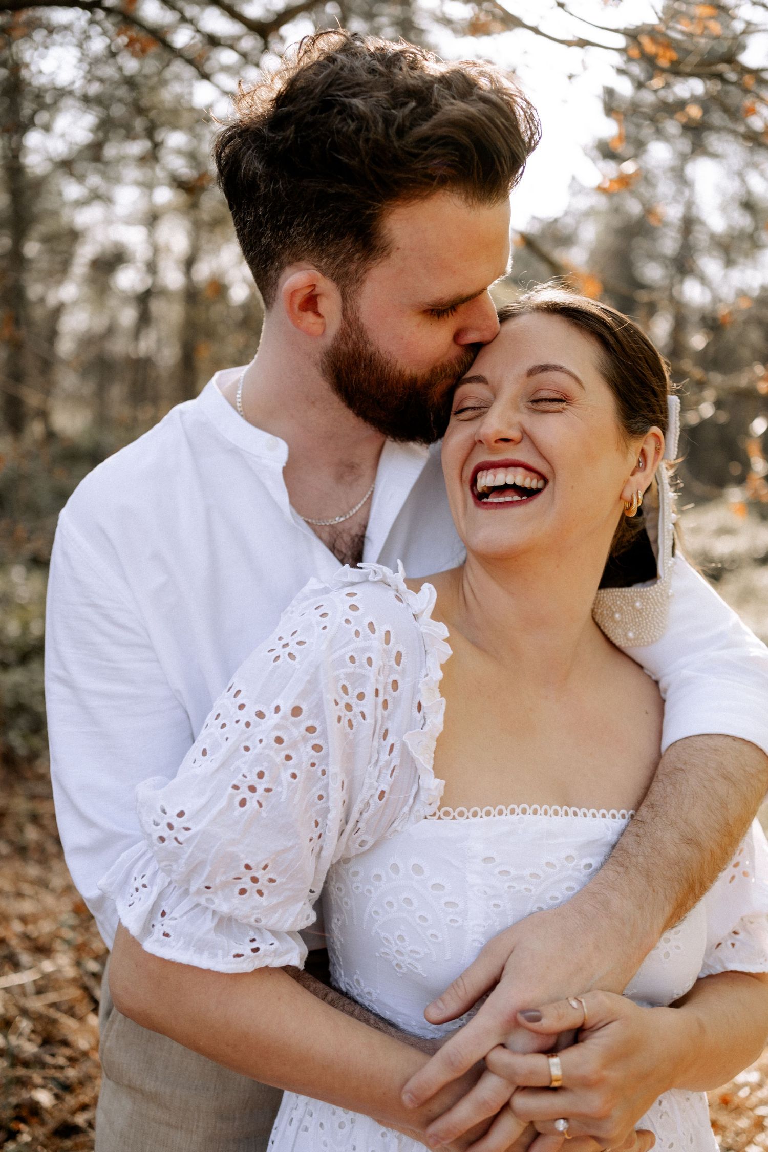 Couple in love, man kissing his female partner on the forehead who is smiling and looks happy and in love in the woods in Surrey