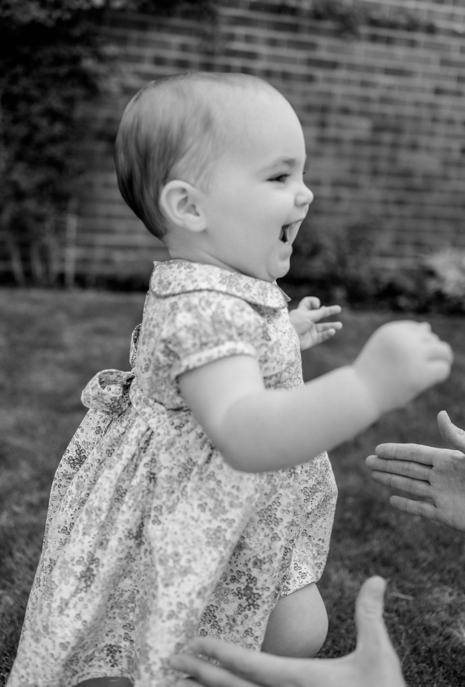 One year old girl running through her garden into the arms of her mum with a big smile on her face at their home in Surrey