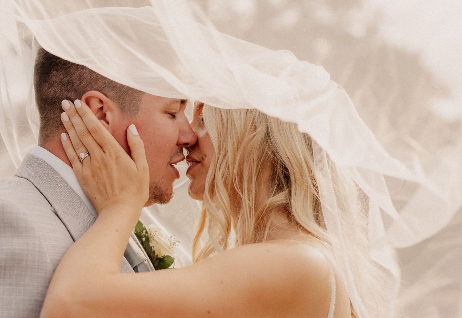 Bride and groom kissing underneath veil at Milton Hill House, Oxfordshire