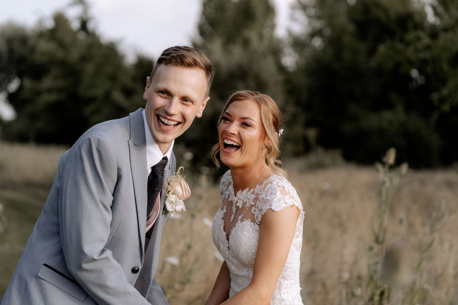Groom and bride in a candid photo at their wedding at South Farm Royston, Hertfordshire. Both are looking at their guests, laughing
