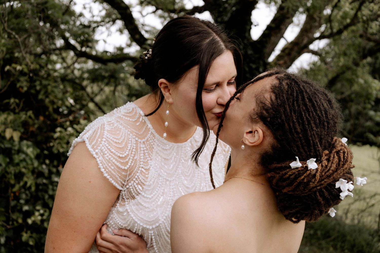 Two brides kissing each other during a first look at their wedding/bridal getting ready at the Secret Barn in Steyning, Sussex