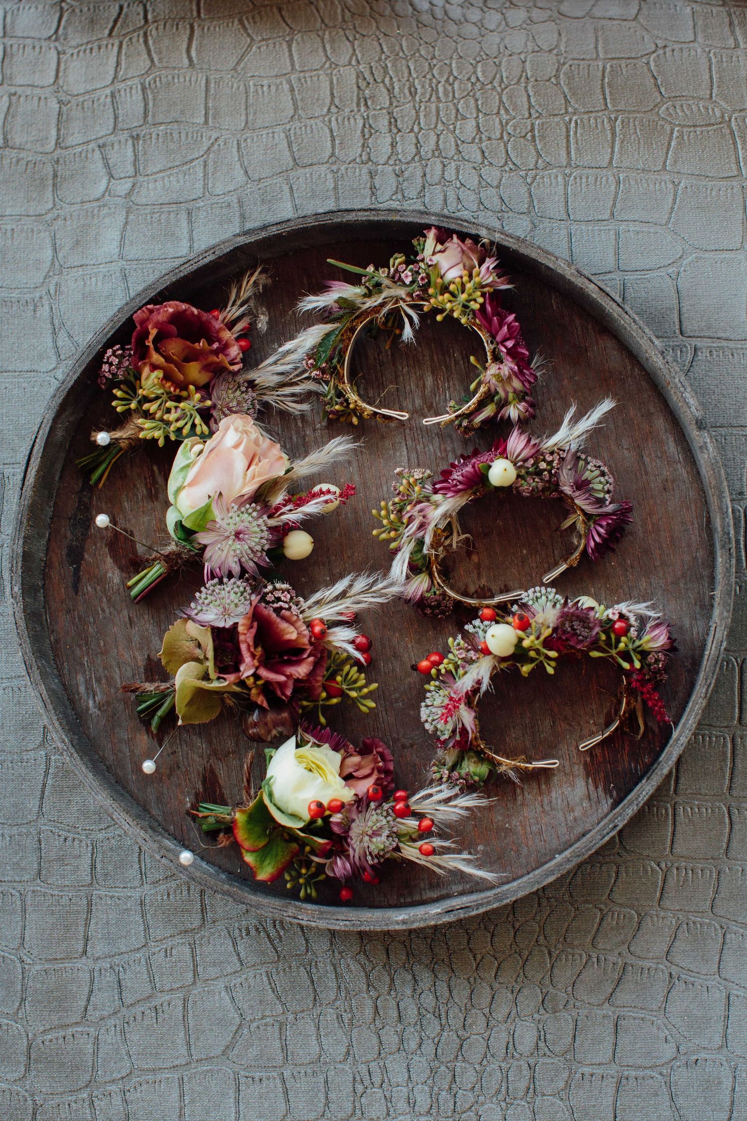Rustic wooden trays display delicate floral arrangements with dried flowers and berries in a decorative sequence.