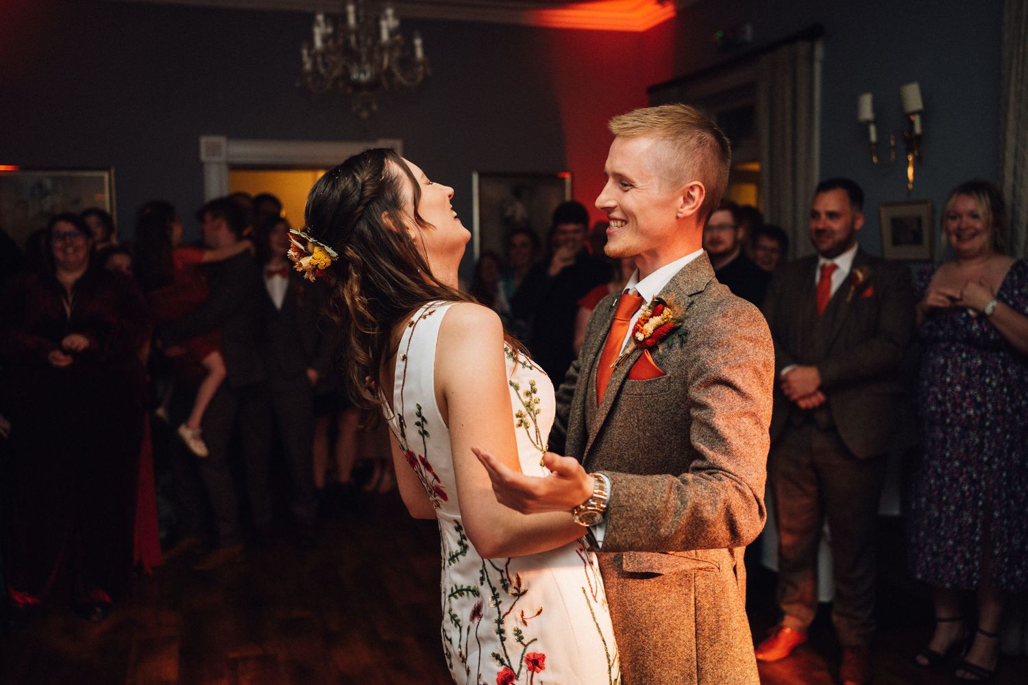 Couples dancing at a wedding reception under warm lighting and chandeliers.