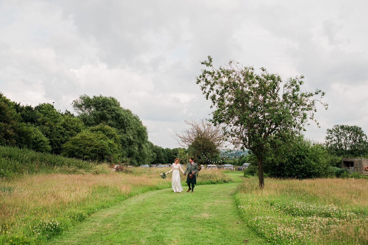 Rolling green hills and trees create a scenic countryside landscape at an outdoor wedding venue.