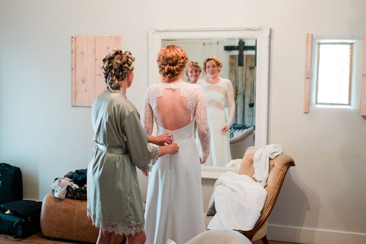Wedding preparation scene with a full-length mirror reflection in a bright room.