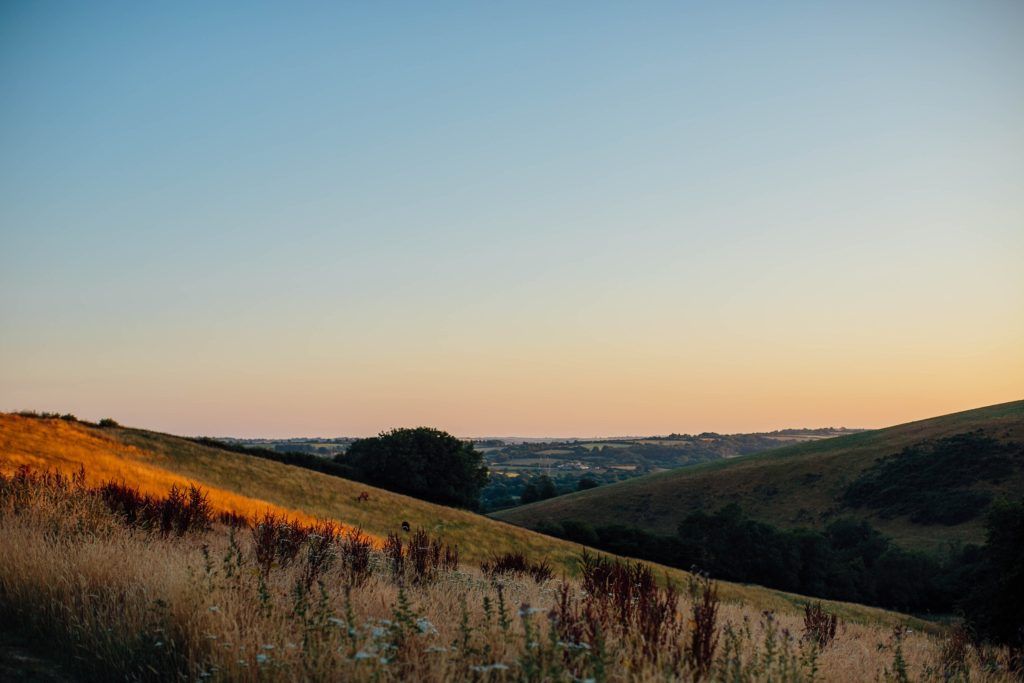 Rolling hills and mountains at sunset with golden light casting across the landscape.