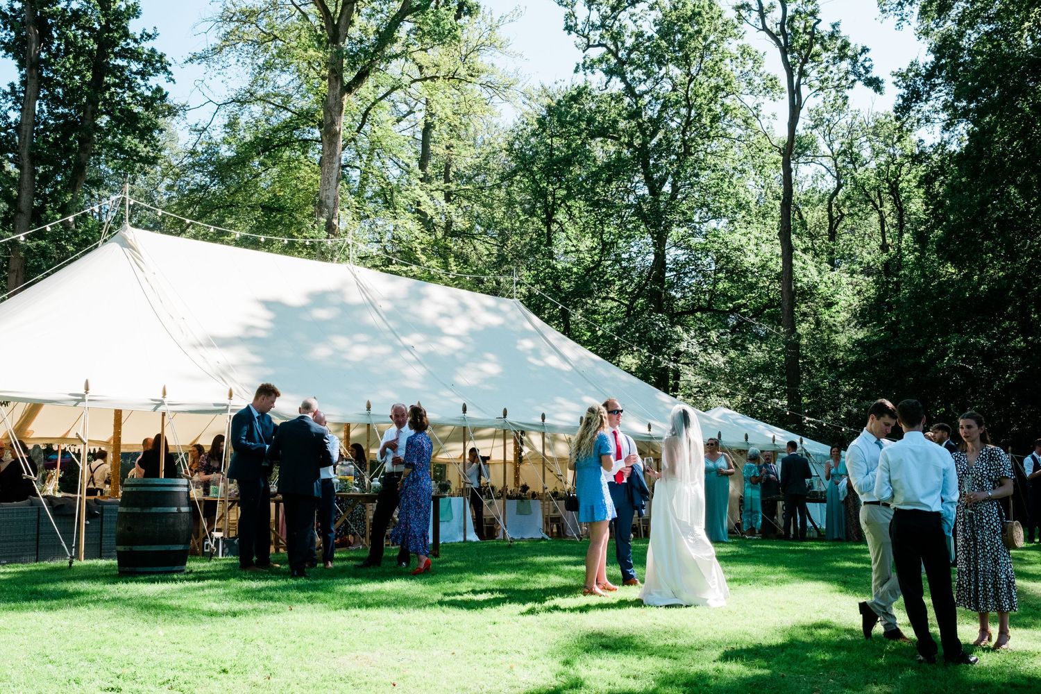 White wedding tent set up outdoors surrounded by lush green trees and natural scenery.