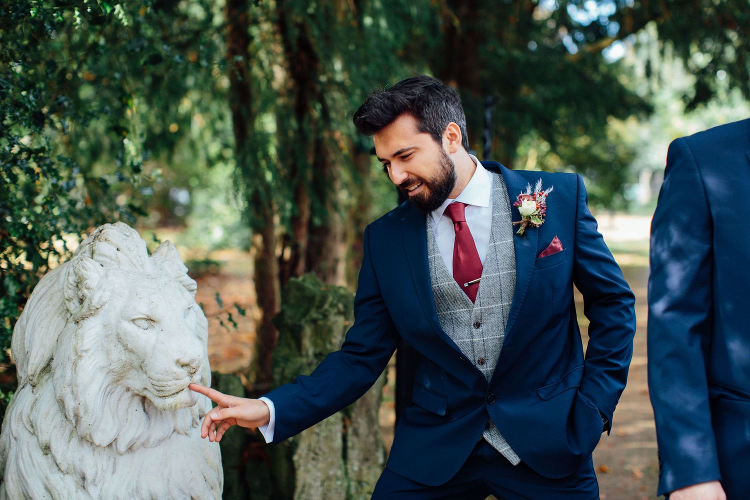 Groomsmen posing with decorative stone lions in a garden setting.