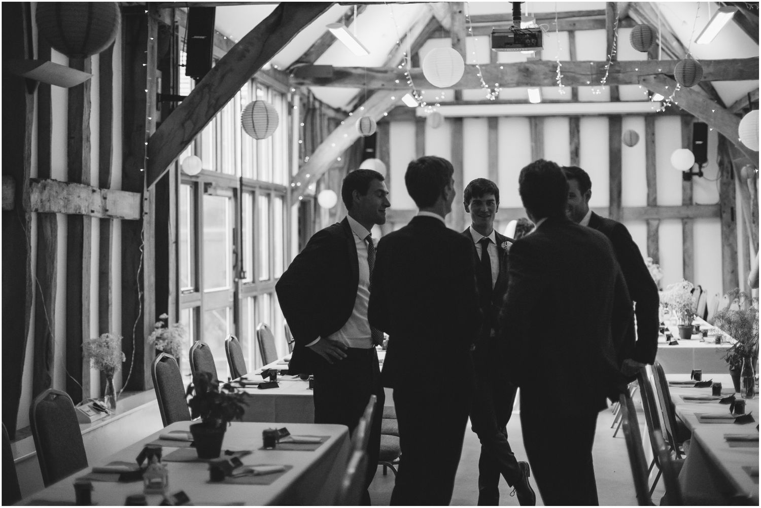 Wedding guests gathered in a light-filled barn with exposed wooden beams.