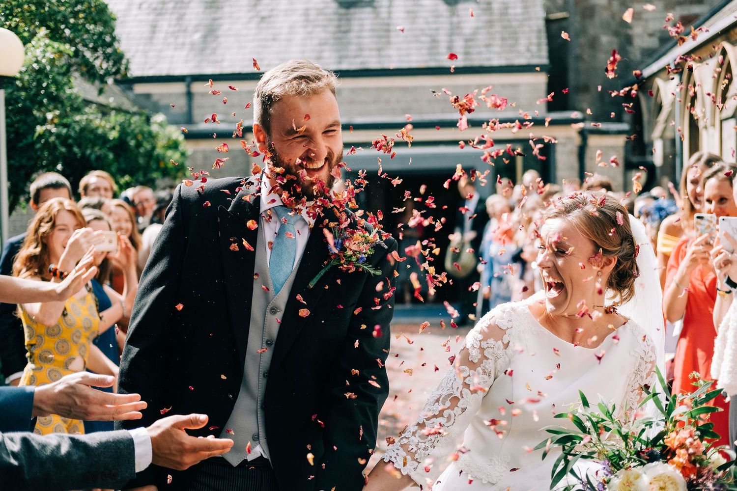 Guests throwing confetti at a joyous outdoor wedding celebration.