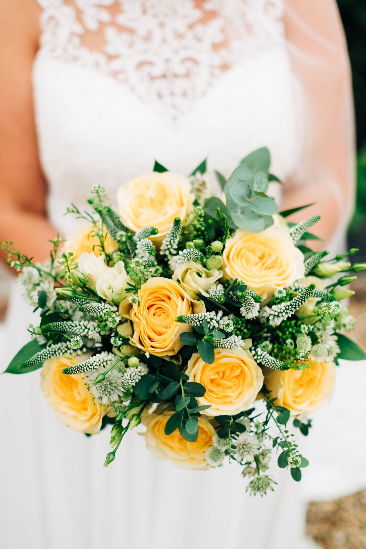 A stunning bridal bouquet featuring yellow roses, eucalyptus, and delicate white flowers.
