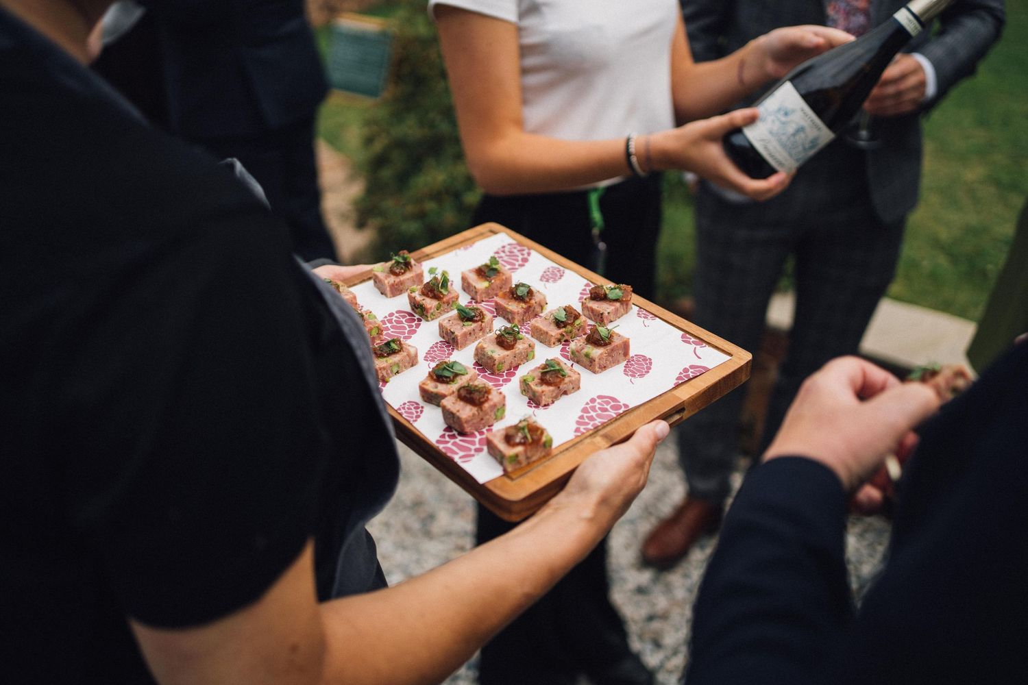 Servers carrying appetizer trays at an outdoor wedding reception.