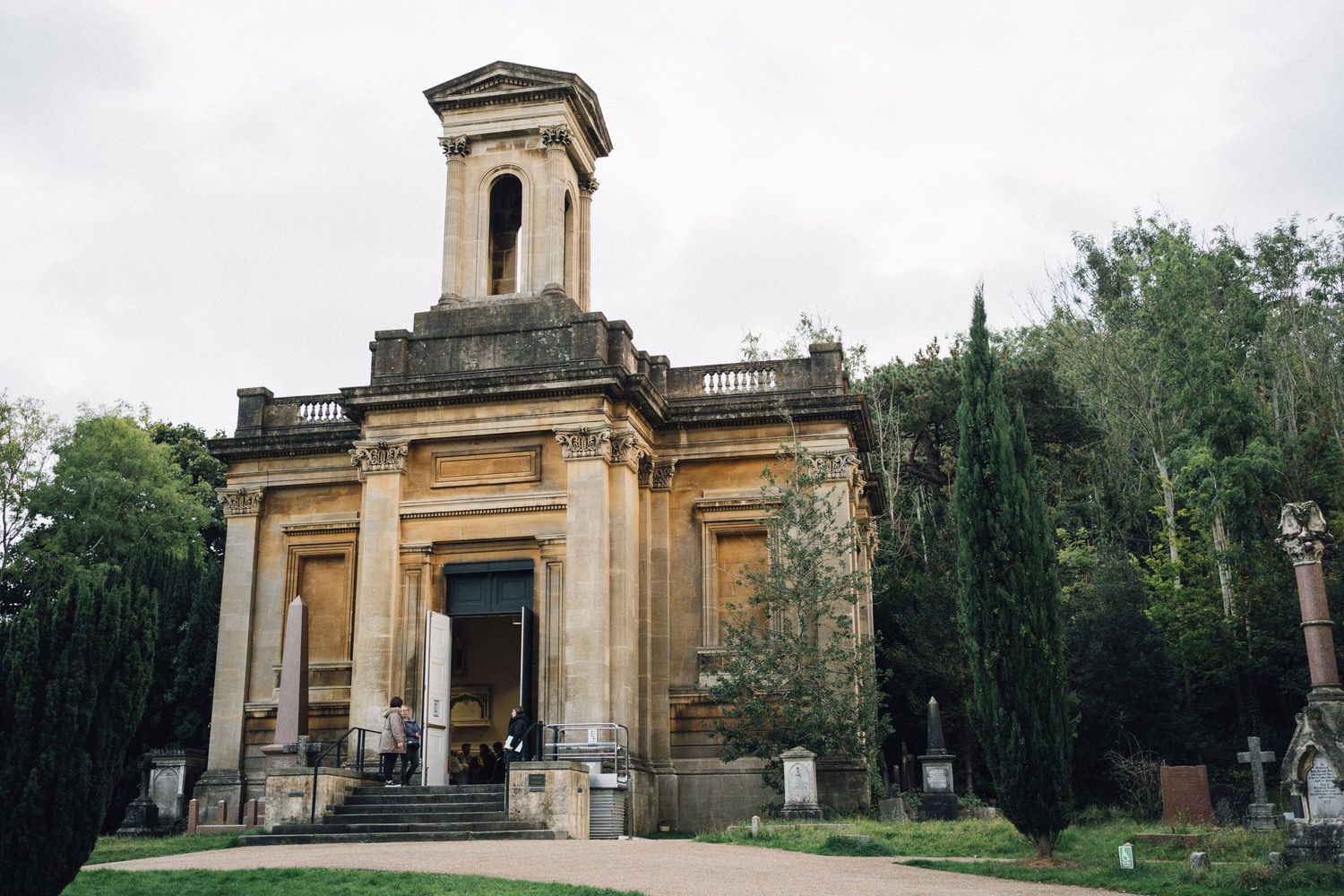 Historic stone chapel with classical architecture and columns set against a cloudy sky.