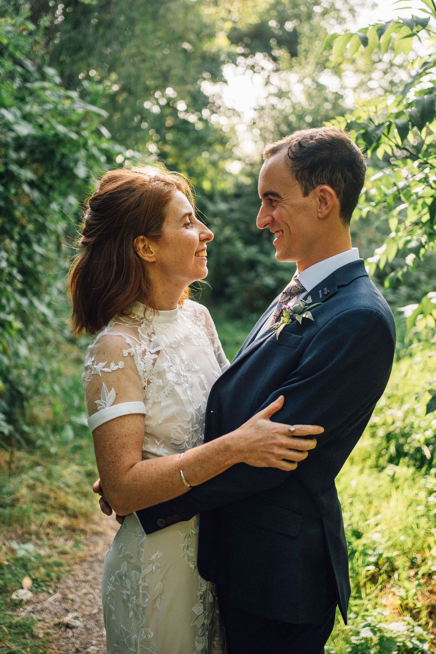 Romantic couple embracing in dappled sunlight among garden foliage.