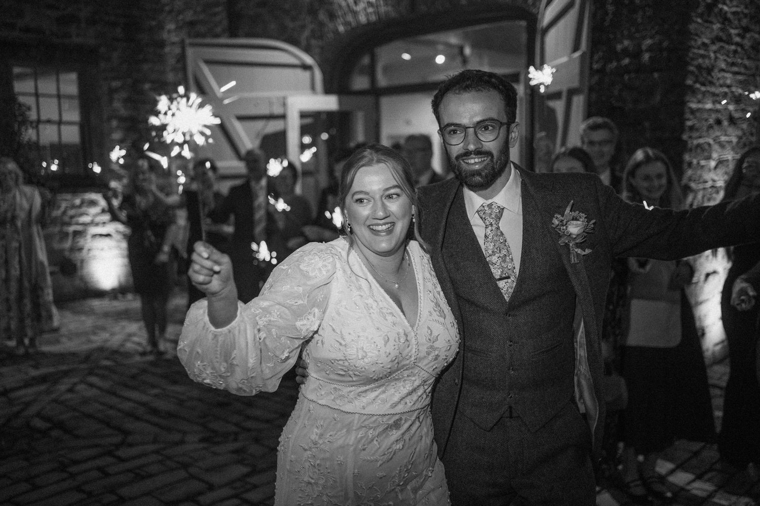 Wedding party dancing and celebrating together during an evening reception in a rustic stone venue.