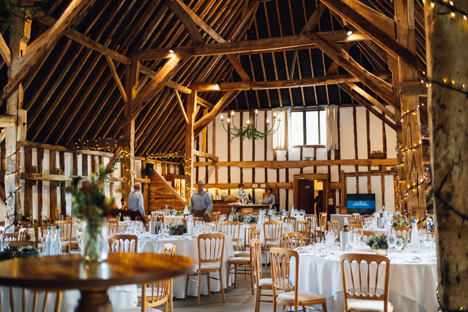 A rustic barn wedding reception venue with wooden beams and elegant table settings.