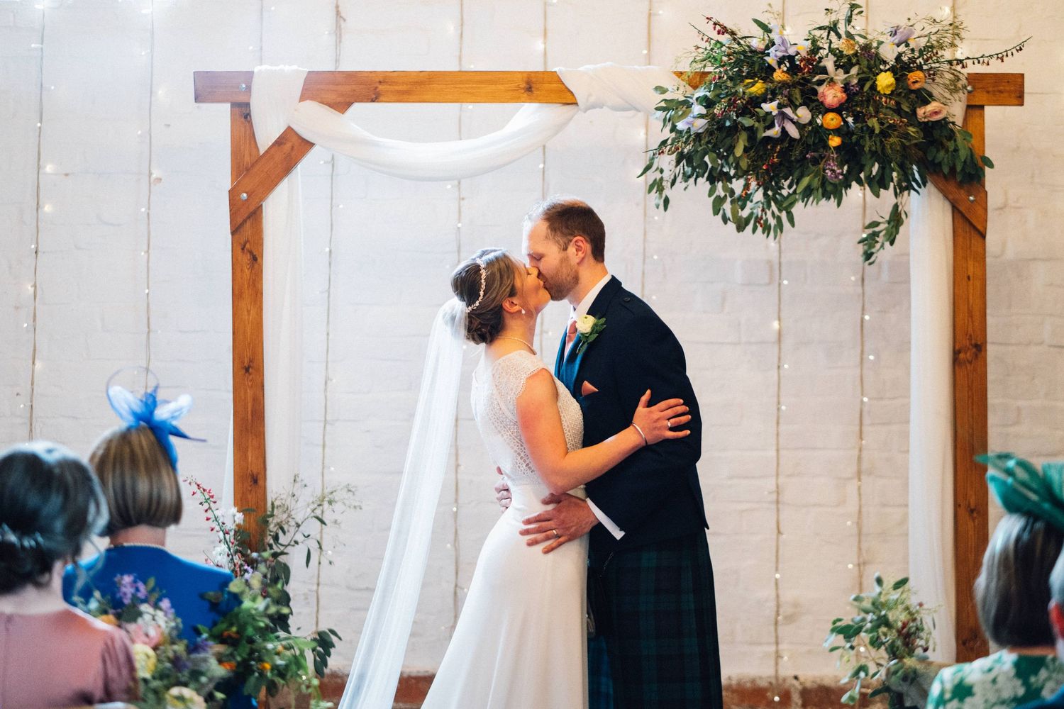 Intimate wedding ceremony taking place in a light-filled rustic barn setting.