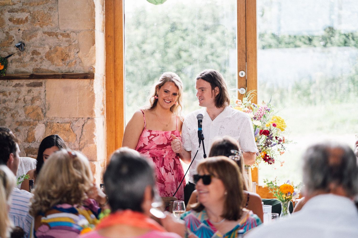 Wedding reception venue with stone walls and large windows letting in natural light.