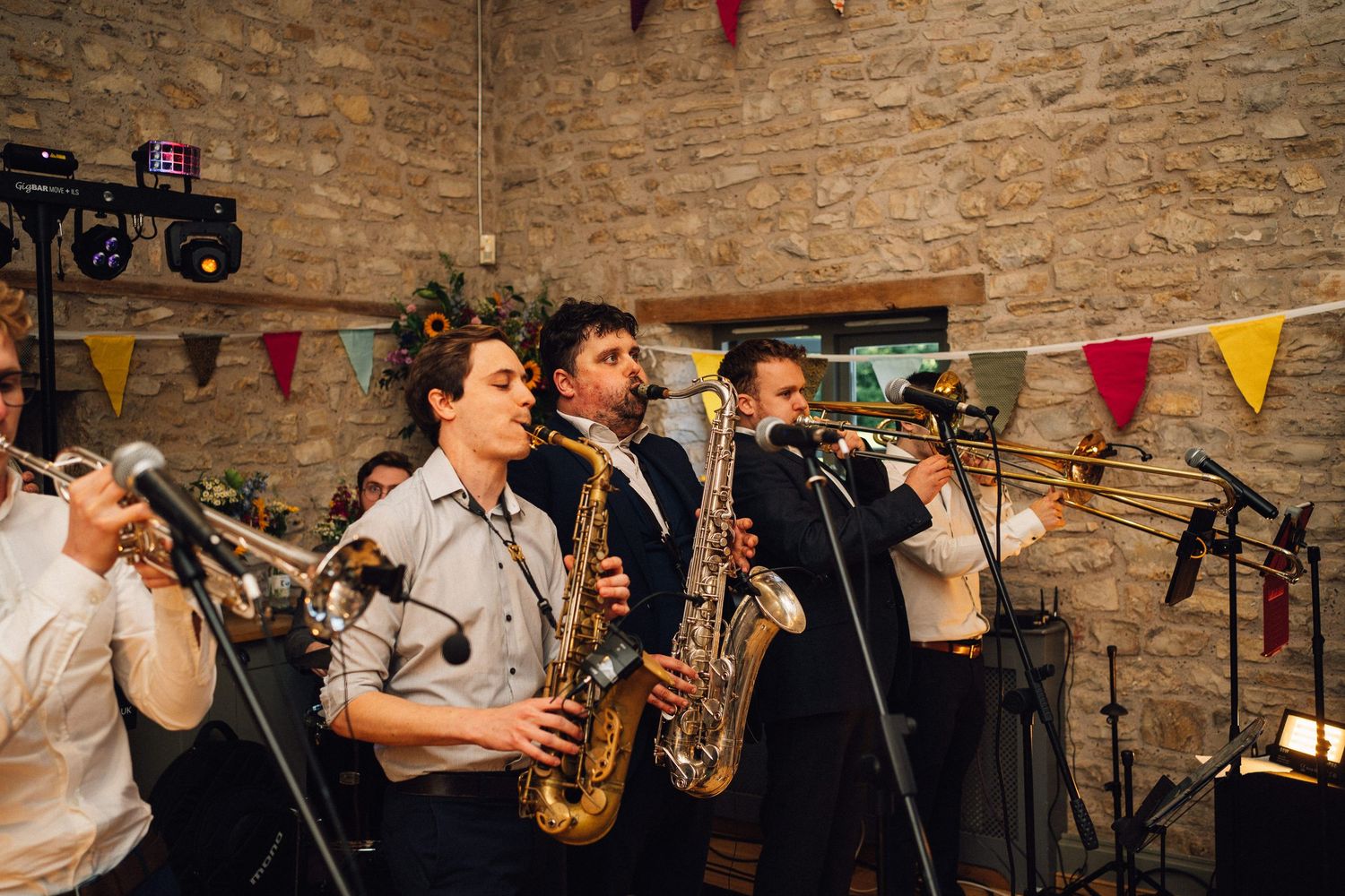 Live band performs at a wedding reception in a rustic stone venue with decorative flags.