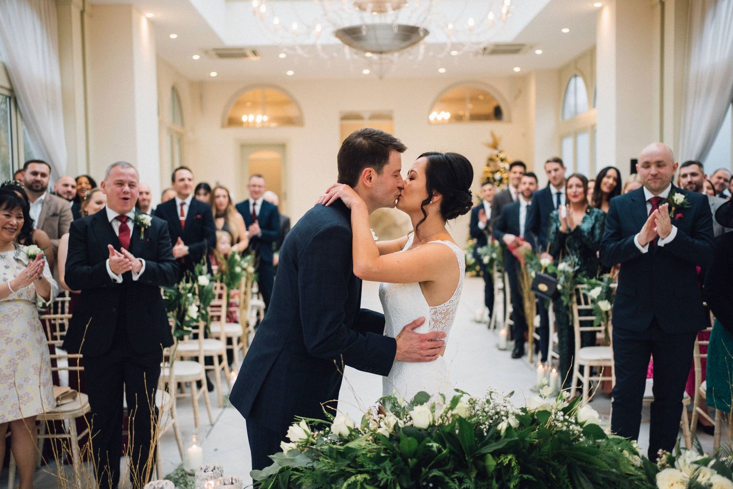 Panoramic view of an elegant wedding ceremony with guests seated in a beautifully decorated hall.