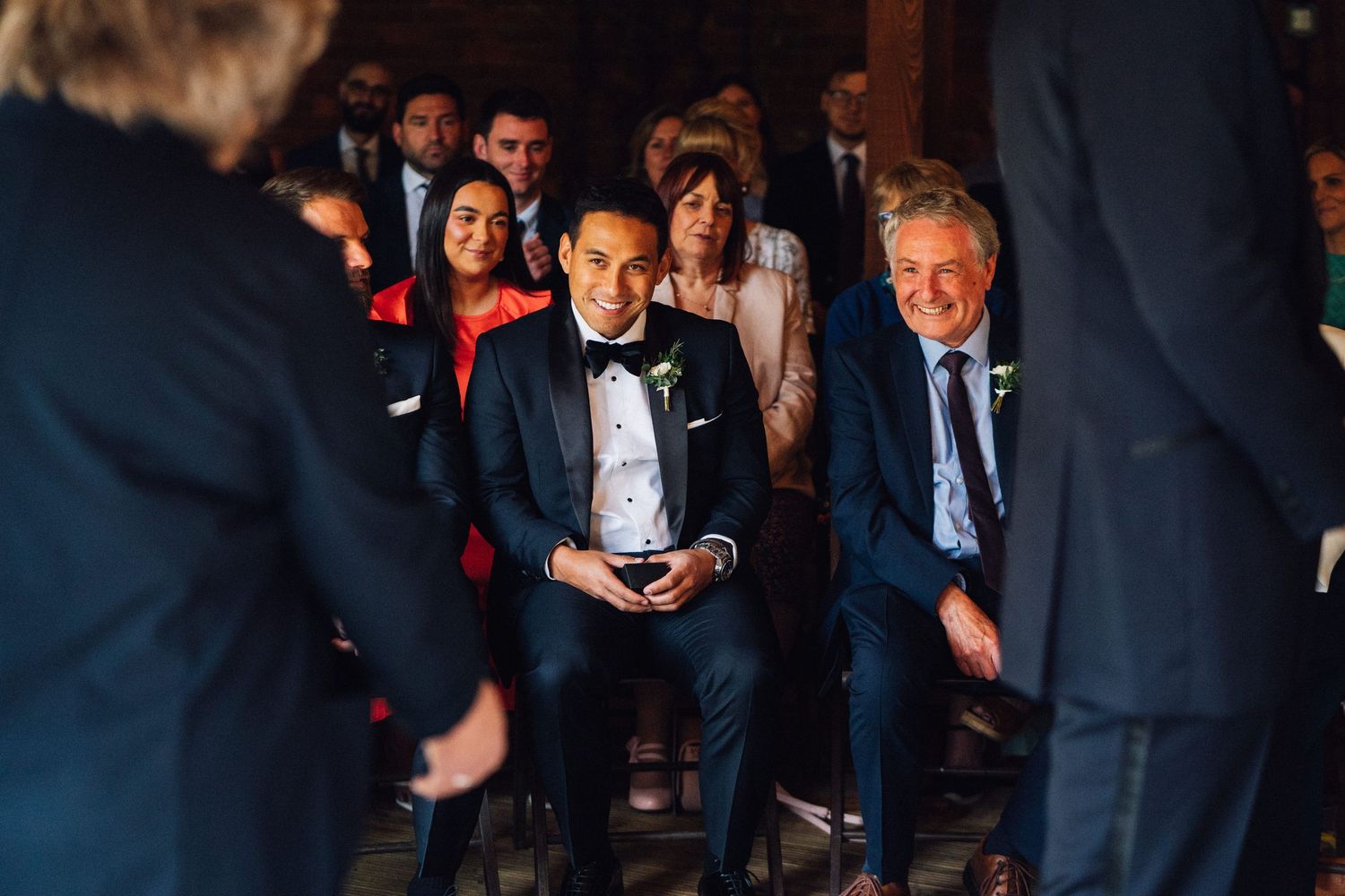 Wedding guests mingling and socializing at an indoor reception venue with warm lighting.