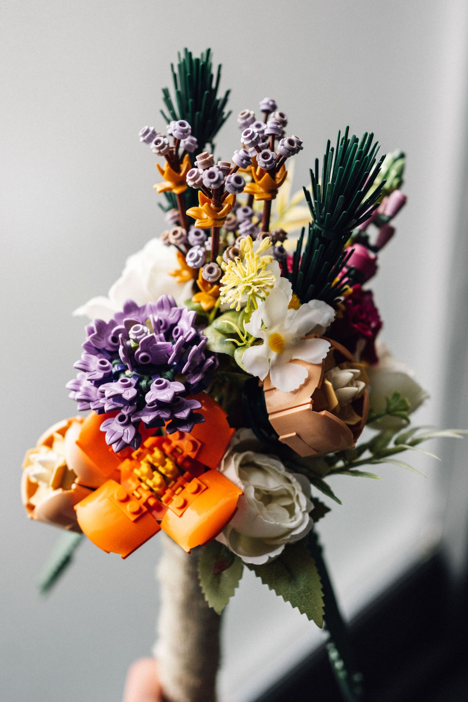 A rustic wedding boutonniere with orange, purple and white flowers accented with evergreen sprigs and wrapped in twine.