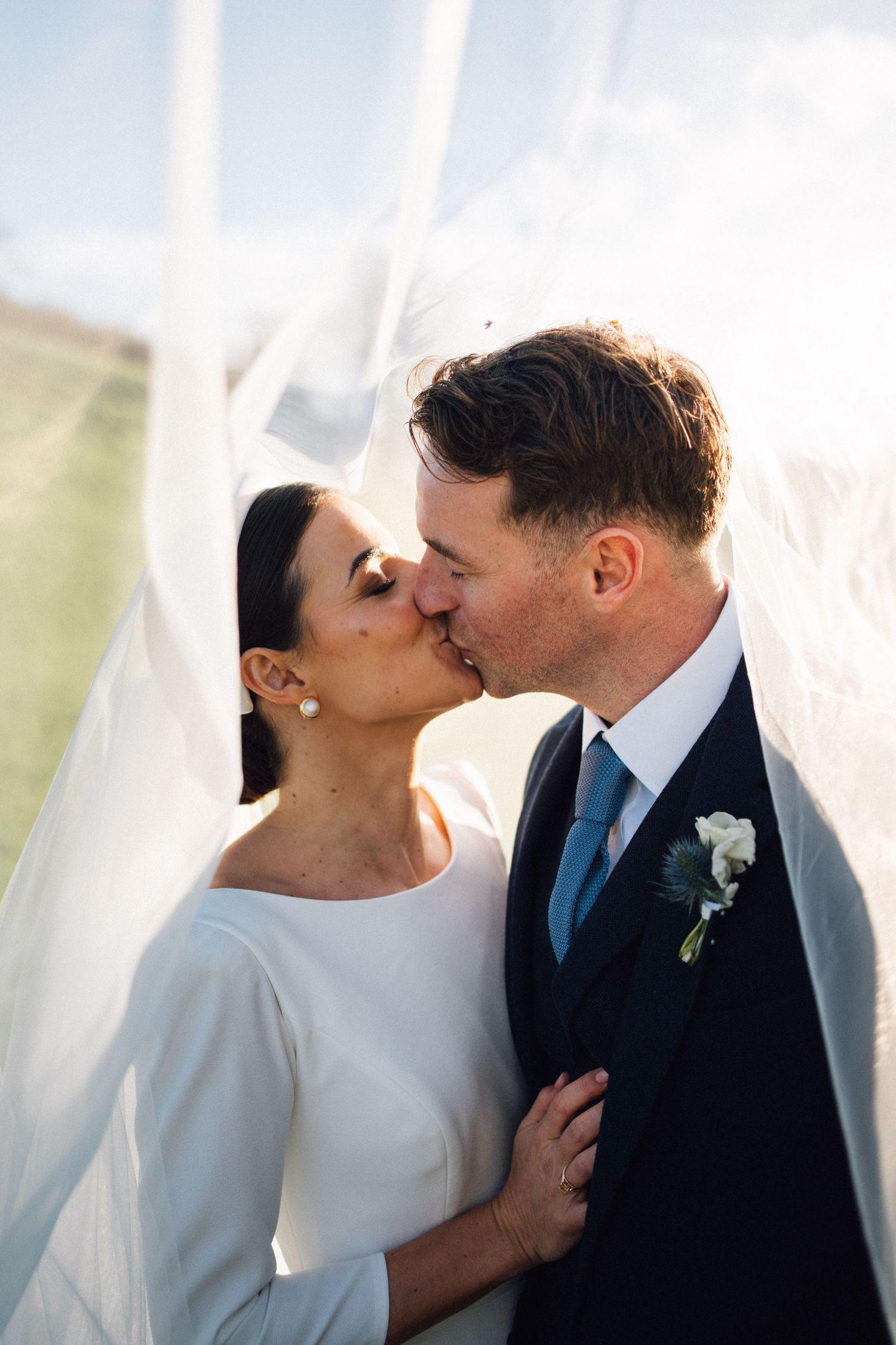 A romantic wedding couple shares intimate kisses behind flowing white curtains in a series of connected photos.