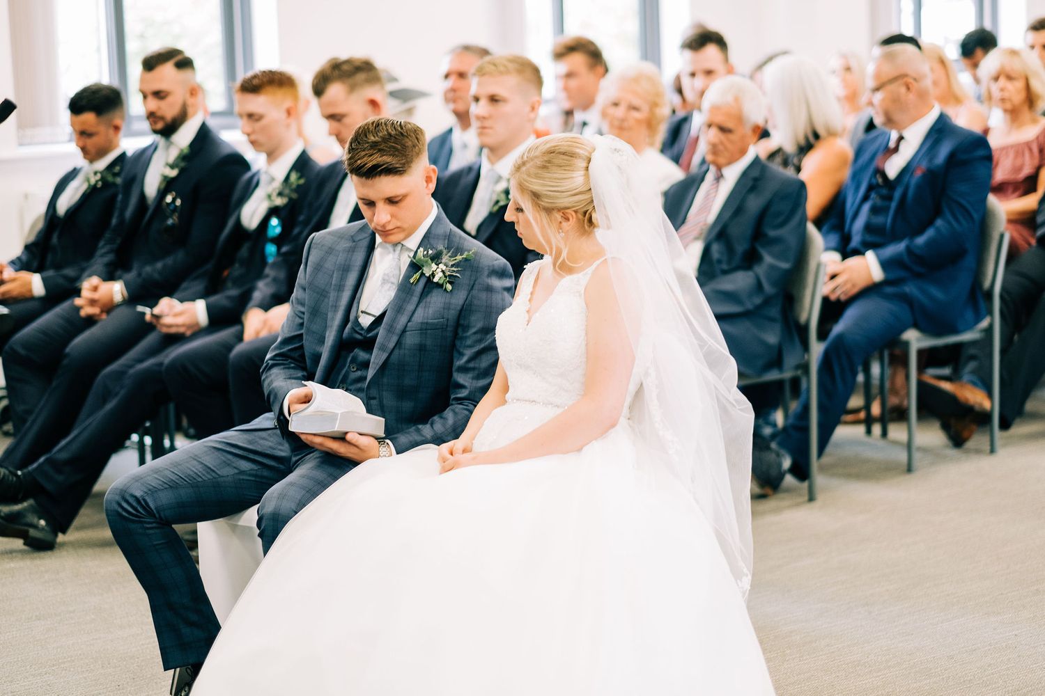 Wedding ceremony guests seated in rows wearing formal attire while watching the ceremony proceedings.