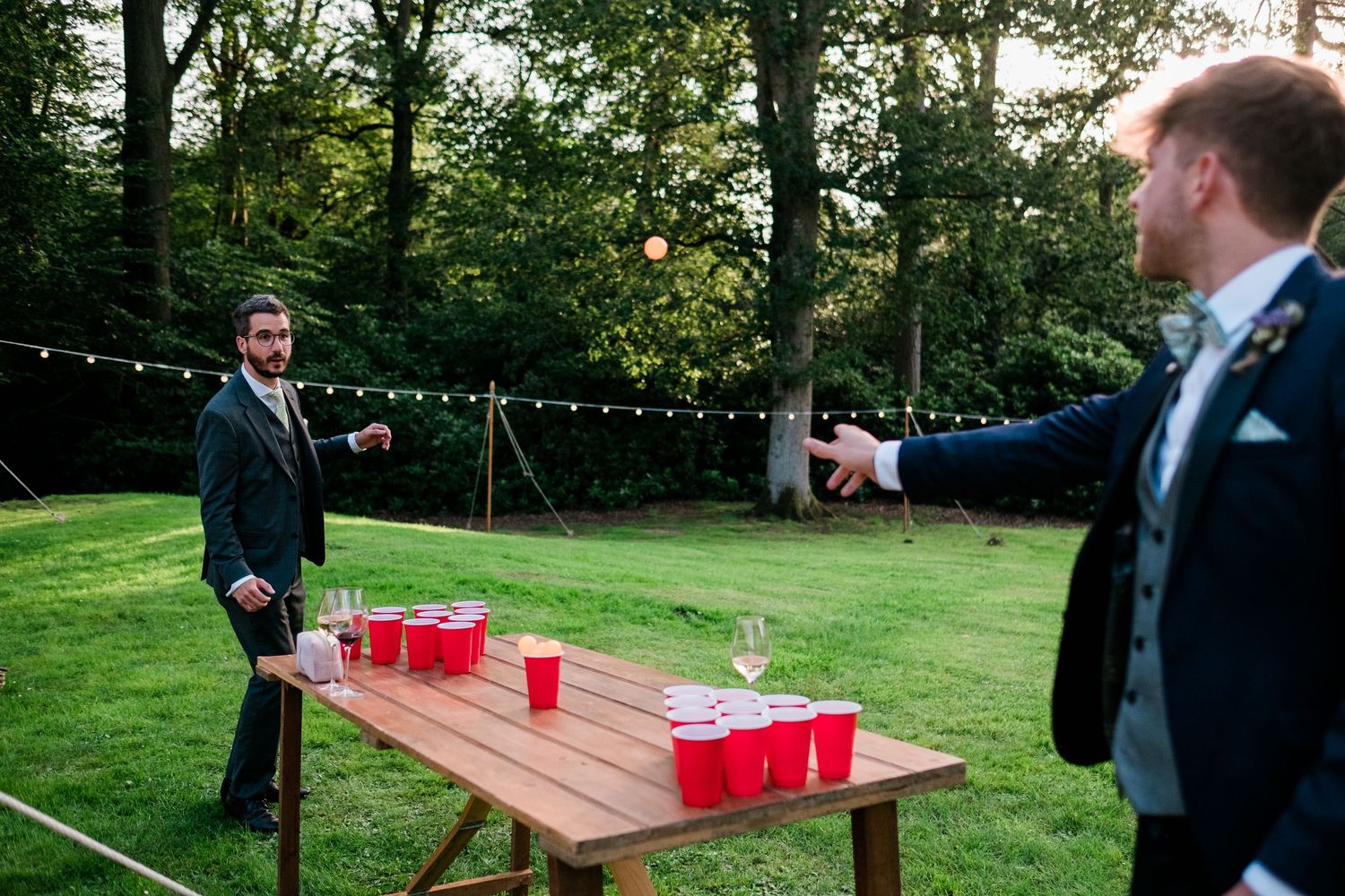 Wedding reception lawn games area featuring red cups and outdoor string lighting.