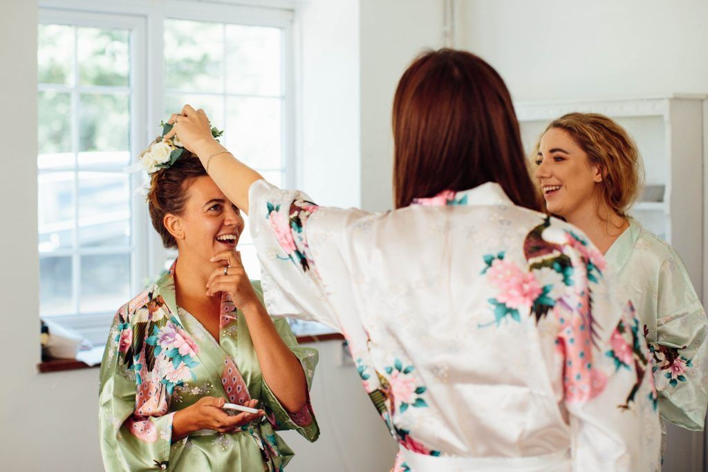Group wearing floral robes laughs and celebrates together in a bright white room.