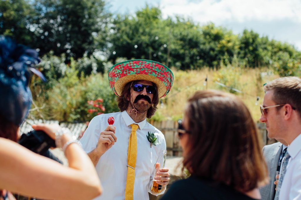 Outdoor celebration with guests enjoying drinks and conversation in a garden setting.