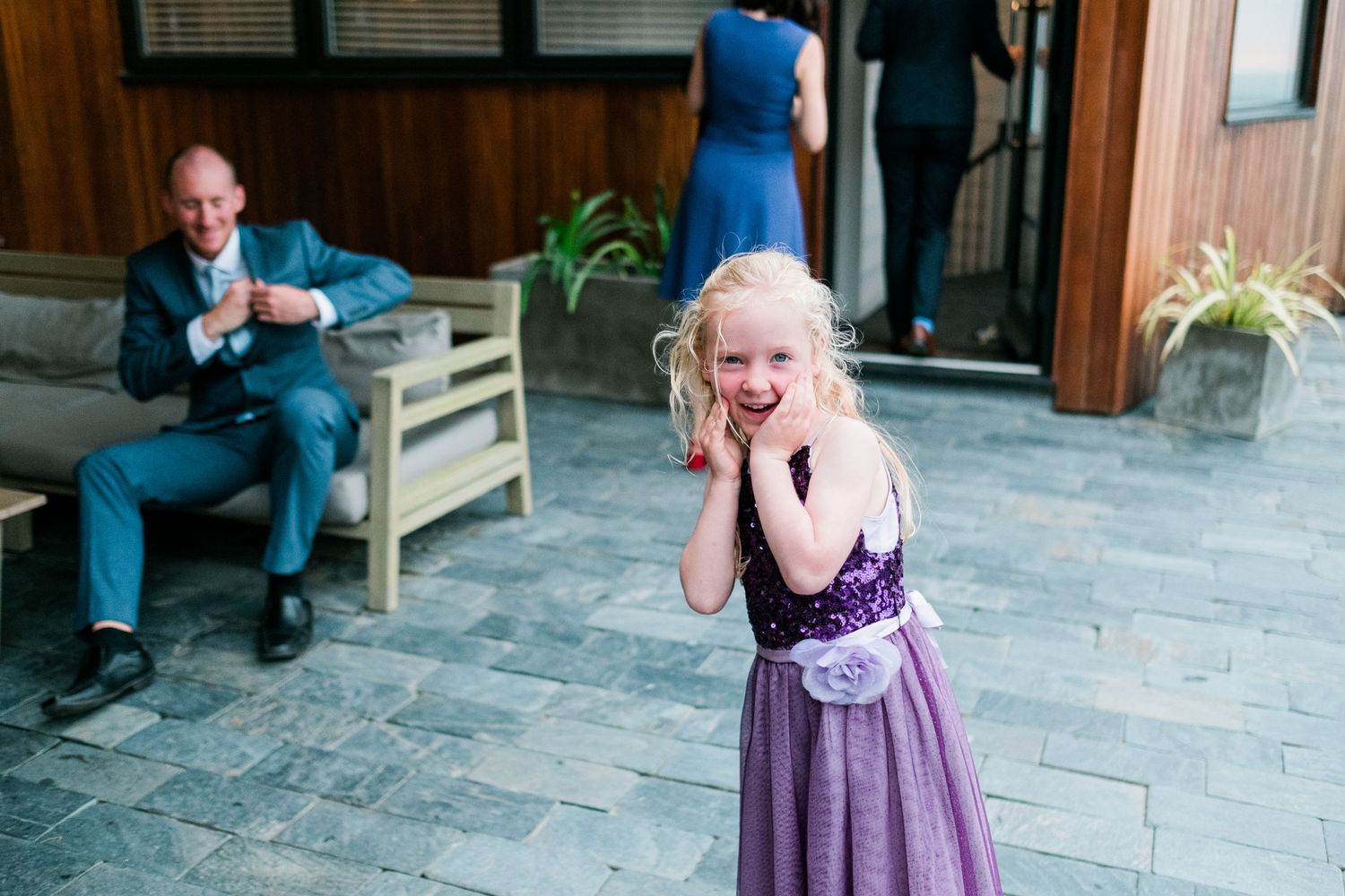 Wedding guests mingling in an indoor venue with stone flooring and natural light.