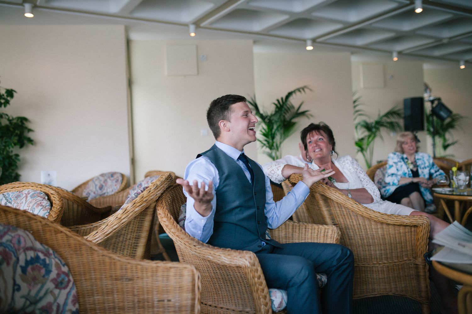 Wedding guests relaxing in wicker chairs during an indoor reception.