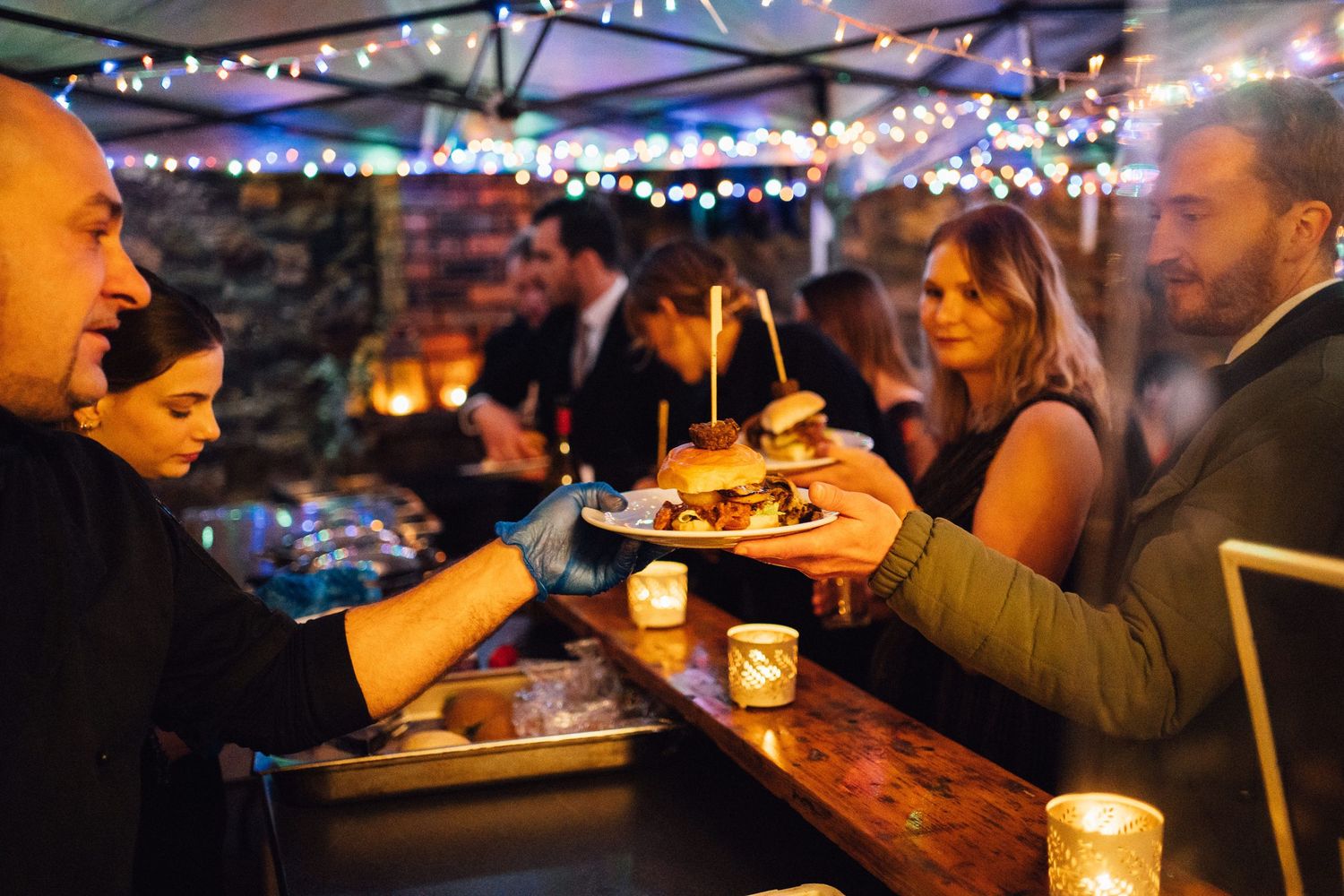 Dimly lit bar scene with string lights overhead and patrons enjoying drinks in a warm, intimate setting.