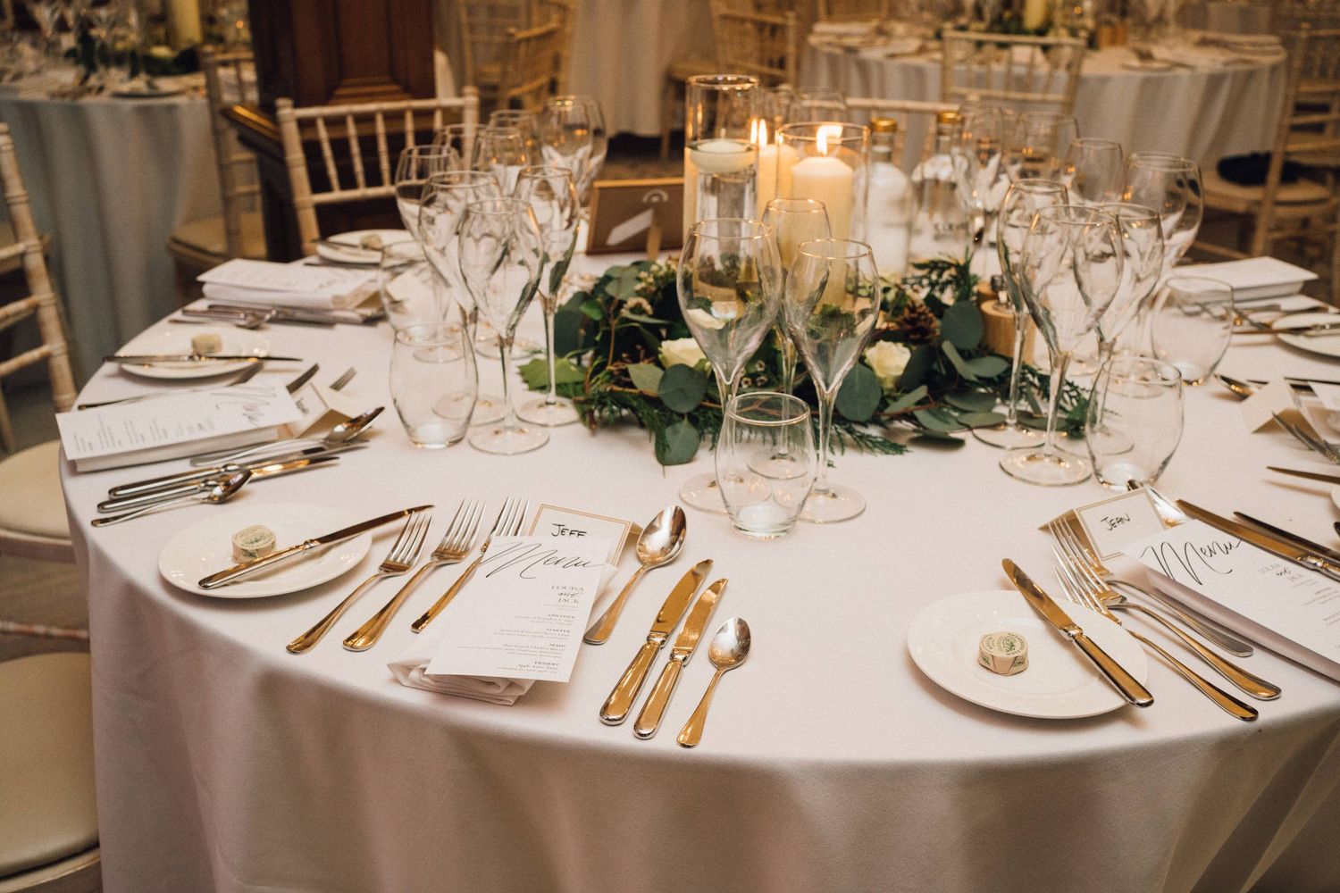 Formal wedding reception tables set with white linens, fine china, and floral centerpieces.