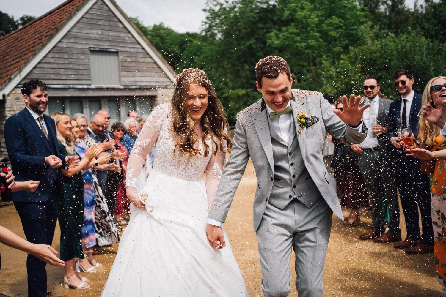 Joyful wedding celebration with guests lining pathway for confetti toss exit.