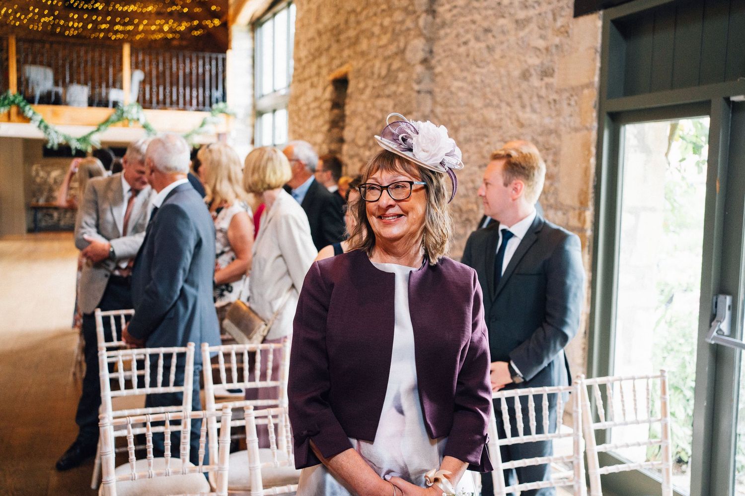 Wedding reception venue decorated with string lights and white chairs in a historic stone building.